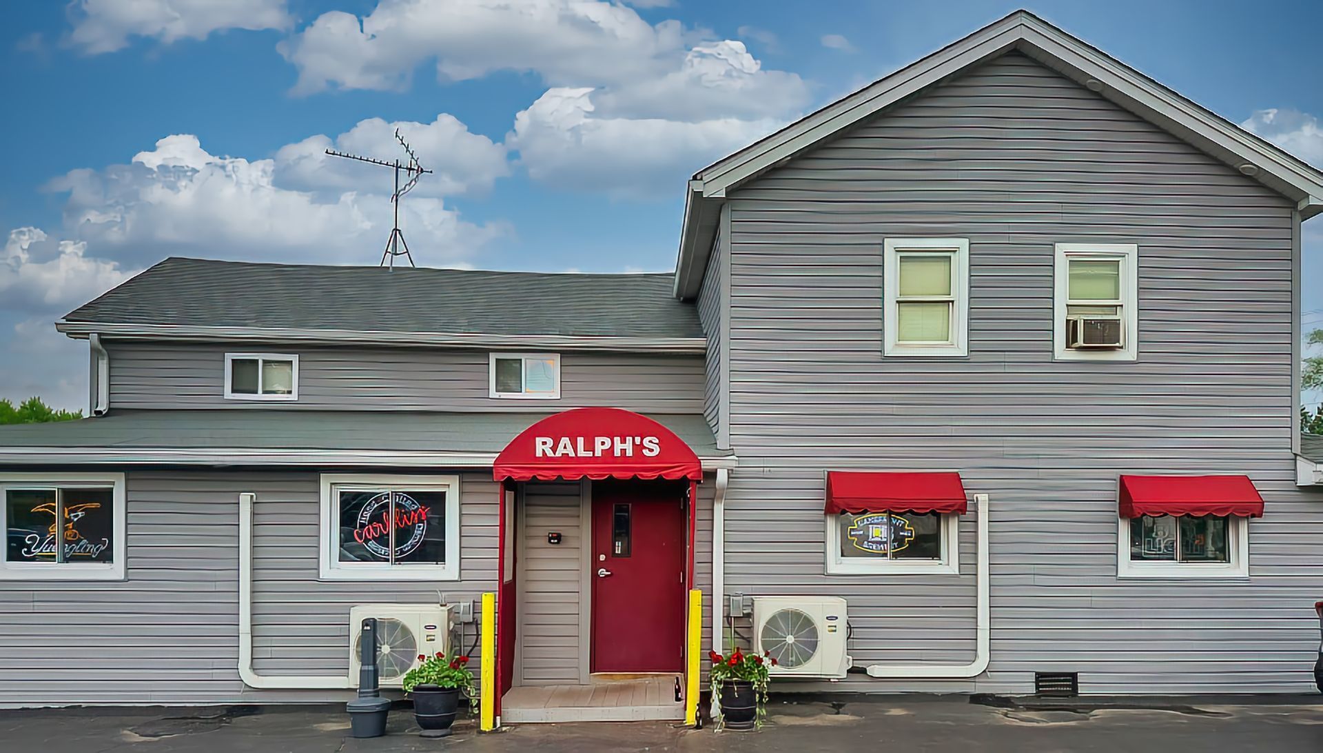 Gray storefront with red awnings and “Ralph’s” entrance under a cloudy sky