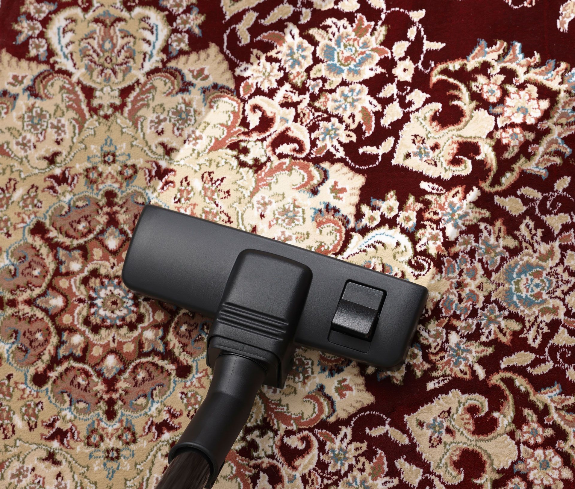 Black vacuum floor head on a patterned red and cream rug