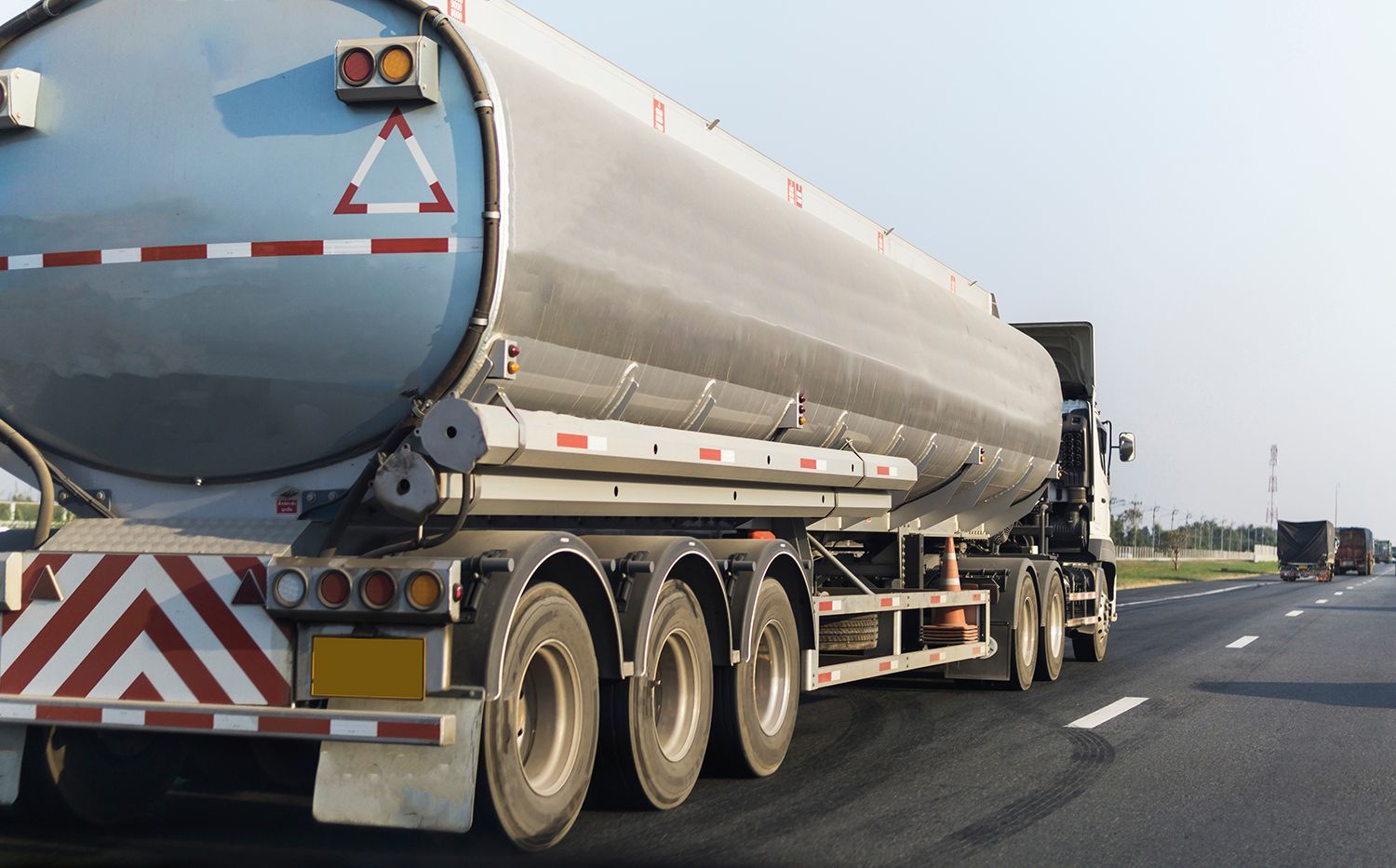 Large tanker truck driving on a highway, transporting liquid cargo with warning markings.