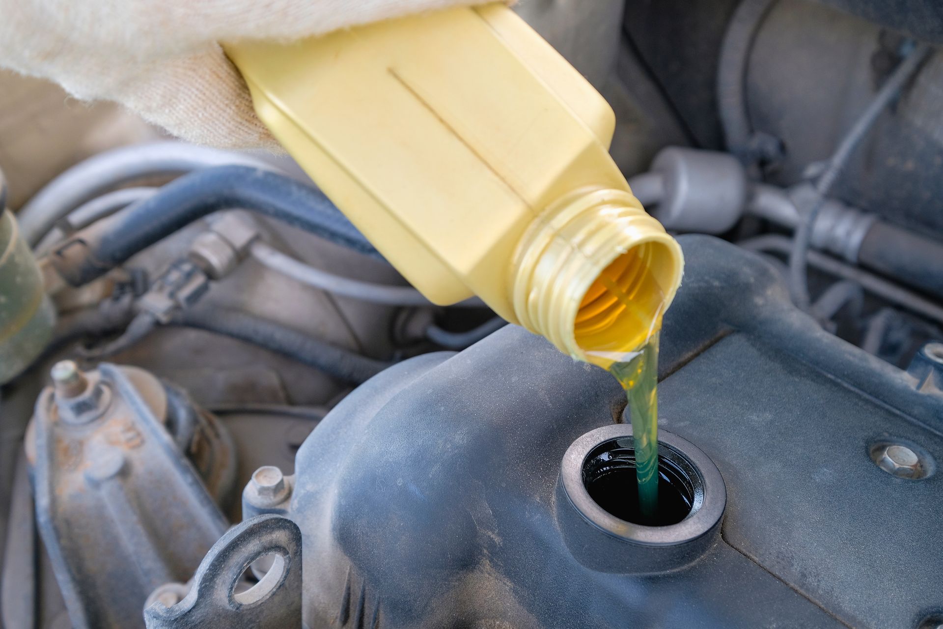 Hand pouring fuel additive into a vehicle engine fuel system.