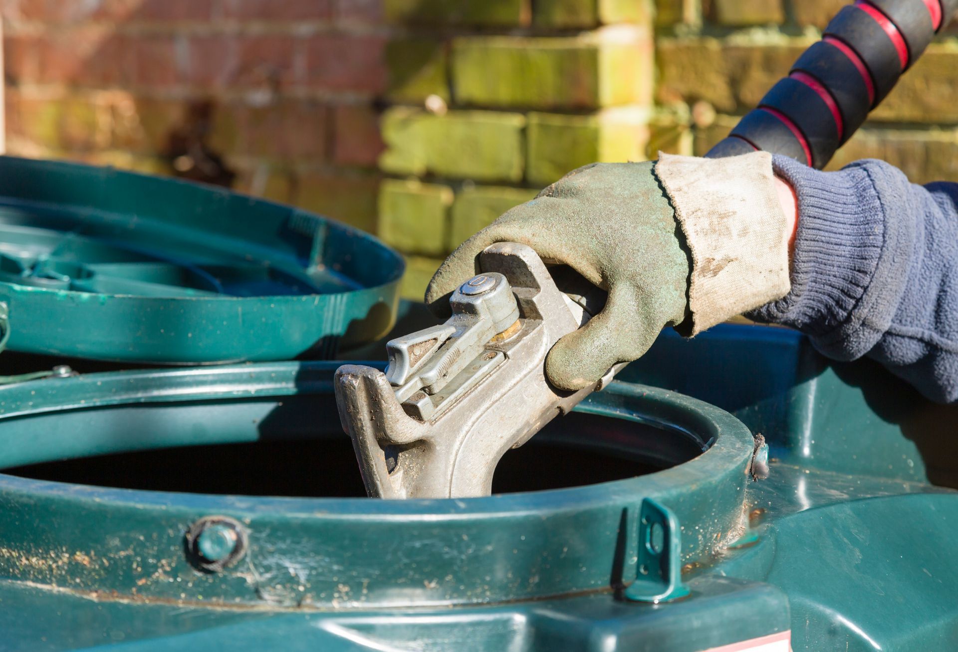 A person is filling a green water tank with water.