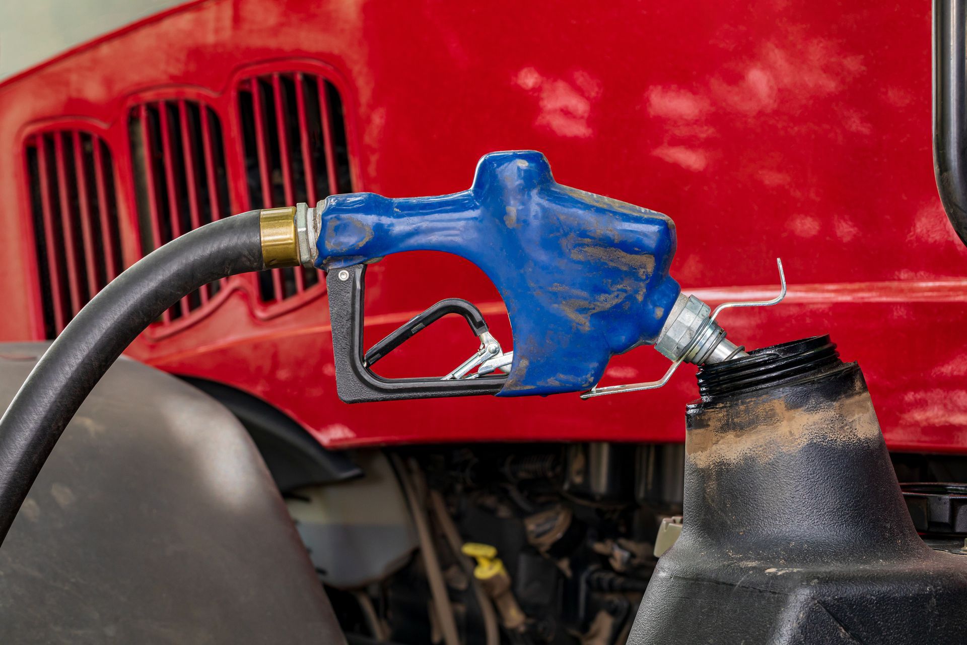A gas pump is attached to the hood of a red truck.