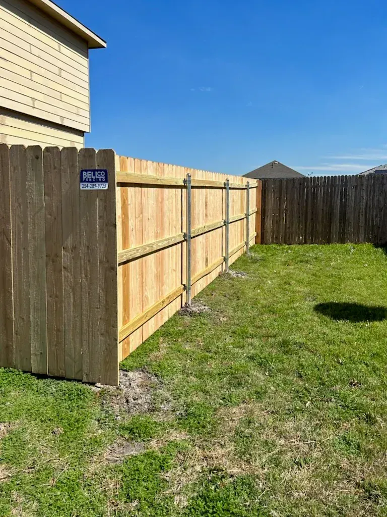 Wooden fence in a backyard under a clear, blue sky.
