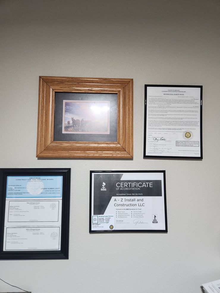 Four framed certificates and a photo arranged in a grid on a light wall.