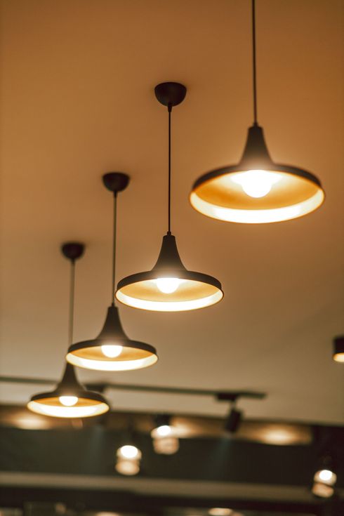 Warm pendant lights hanging from a ceiling in a row, glowing in a dim indoor space