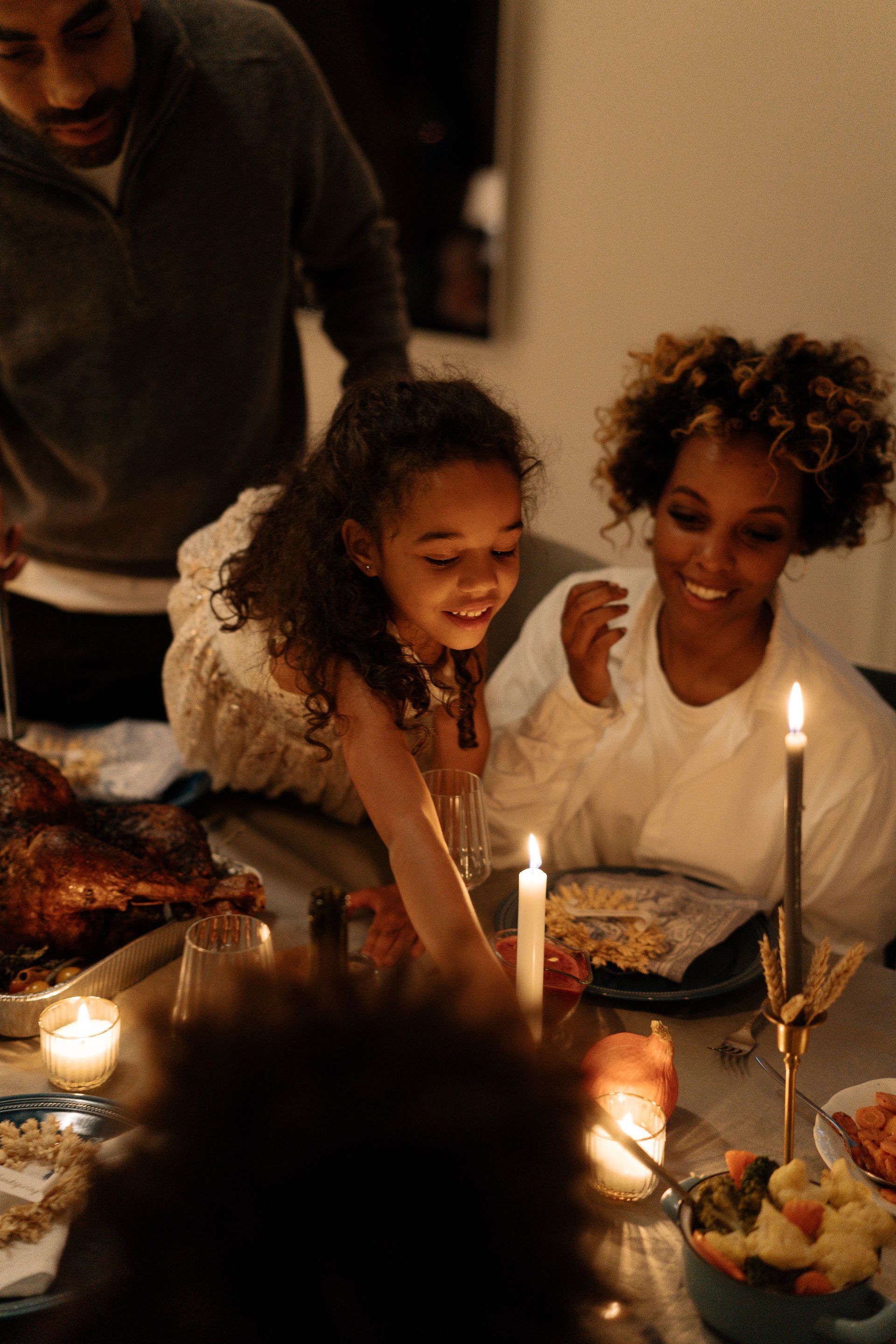 Family gathered around a candlelit table, smiling and celebrating a meal together