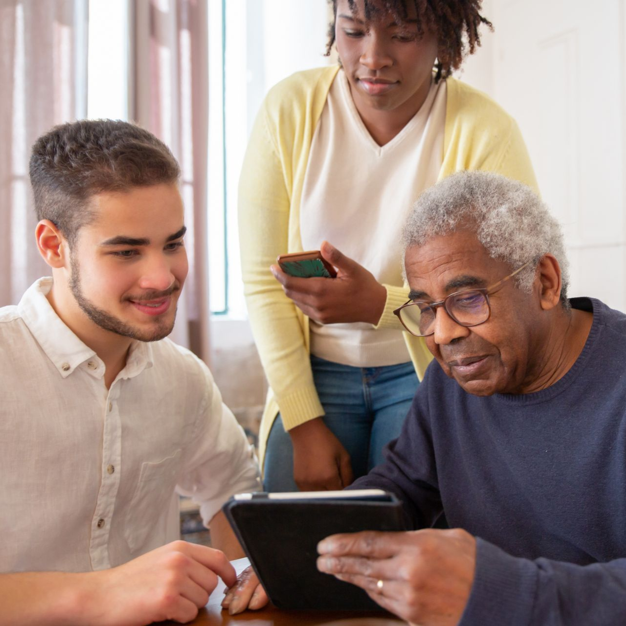 Three people collaborating around a tablet in a bright room