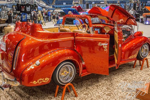 Orange vintage bicycle on display in a stadium, with exhibits and seating in the background
