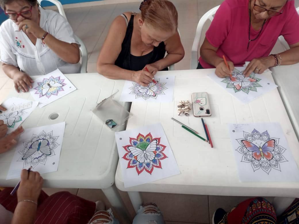 Personas coloreando mandalas en una mesa.