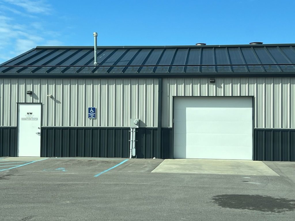 Exterior of a metal building with a white door, garage door, and accessible parking sign.