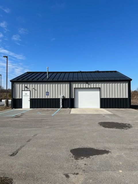 A metal building with a garage door and accessible entrance on a paved lot under a blue sky.