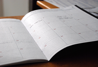 Open planner on a desk, with blank calendar pages.