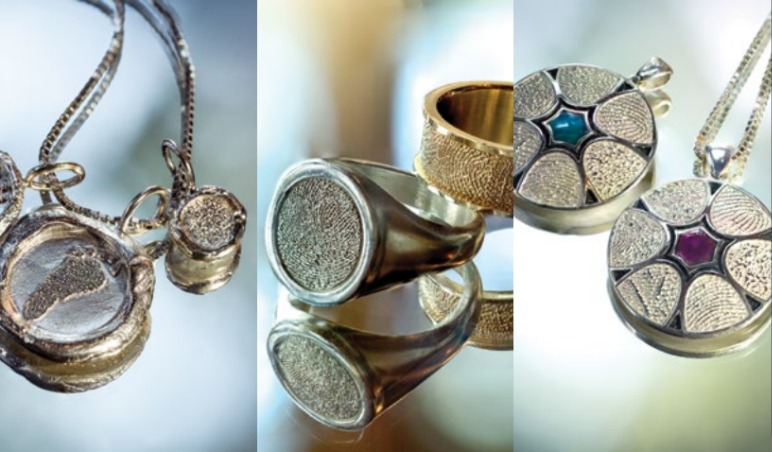 Jewelry: silver pendants with textured centers, golden rings, some with inset stones, displayed on a reflective surface.