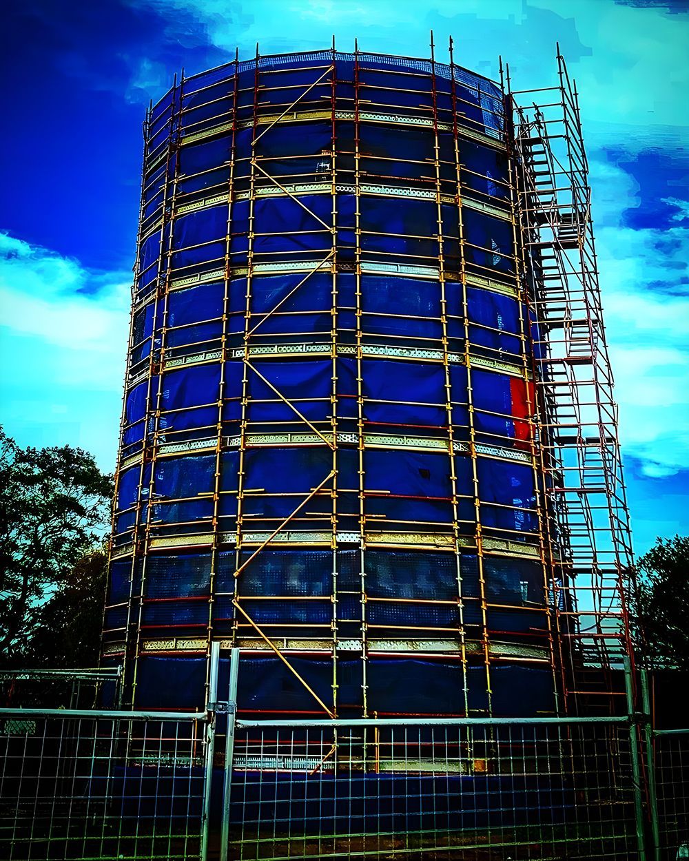 A Tall, Cylindrical Structure Wrapped in Blue Mesh, Covered in Scaffolding — Big River Scaffolding Solutions Pty Ltd in Gold Coast, QLD