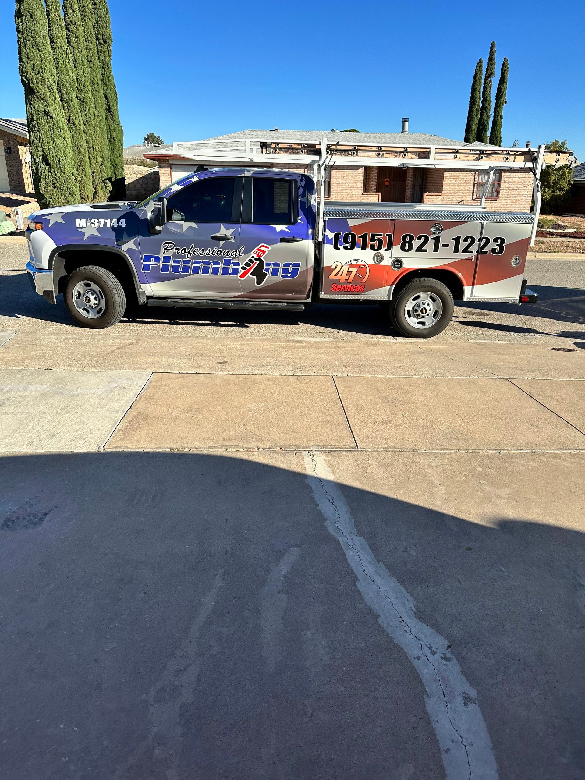 Blue and orange roadside service truck parked in a driveway under a sunny sky