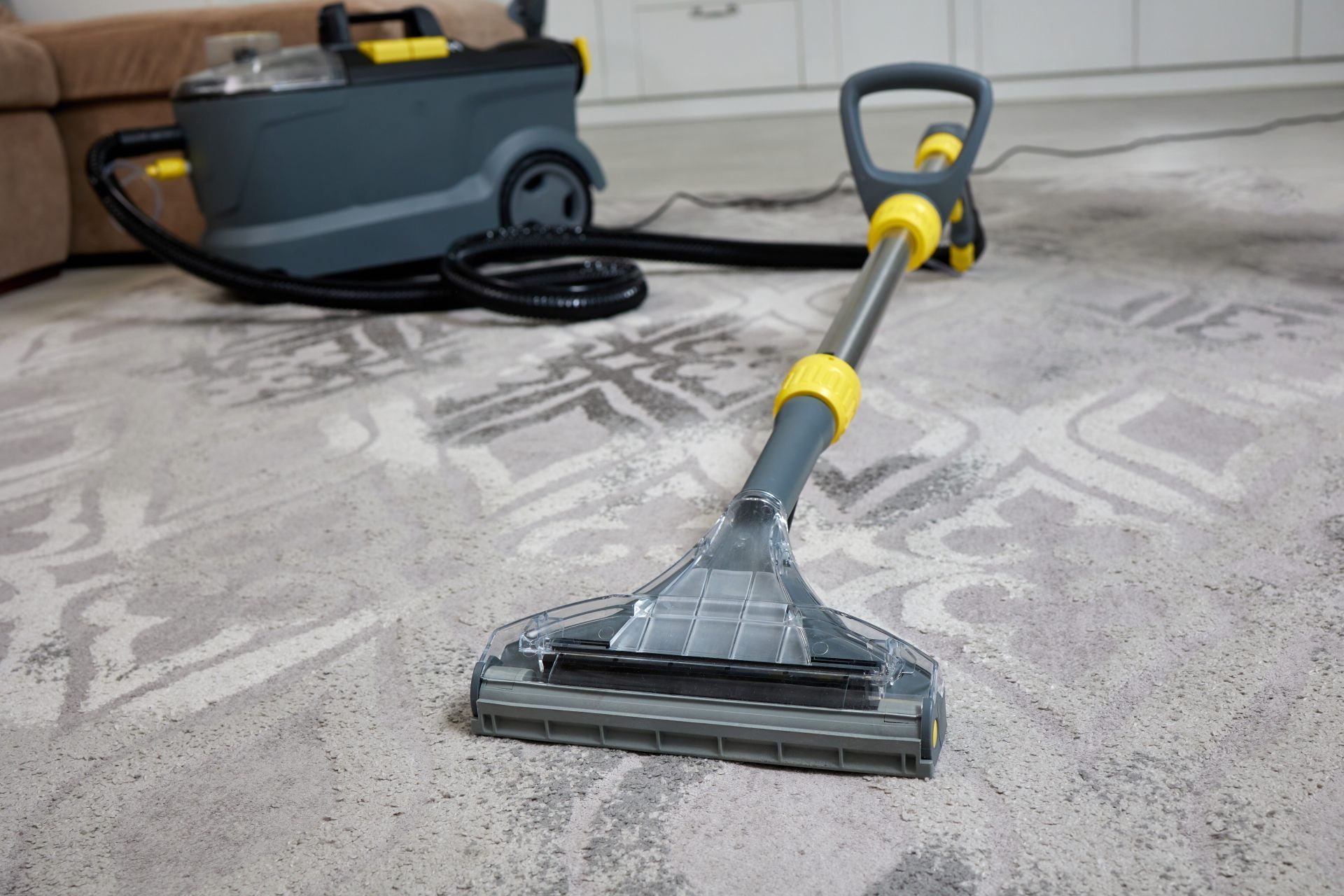 Yellow-and-gray carpet cleaning machine on a patterned rug in a home interior
