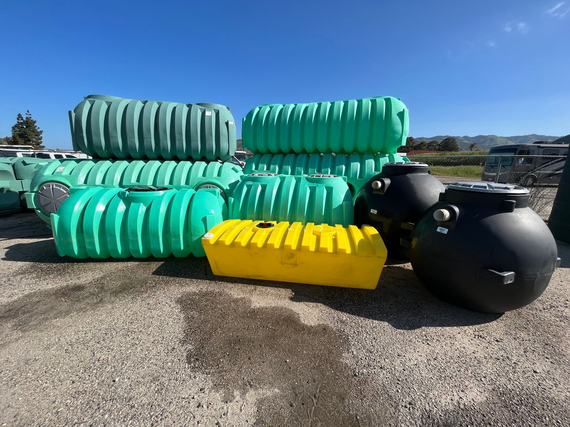 A bunch of green and black plastic tanks are stacked on top of each other.