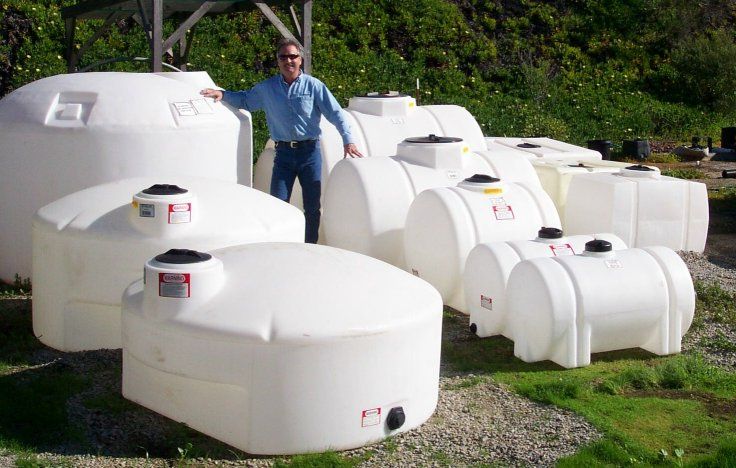 A man standing next to a bunch of white plastic tanks