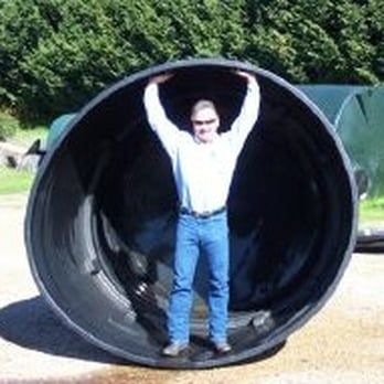 A man is standing in the middle of a large black pipe.