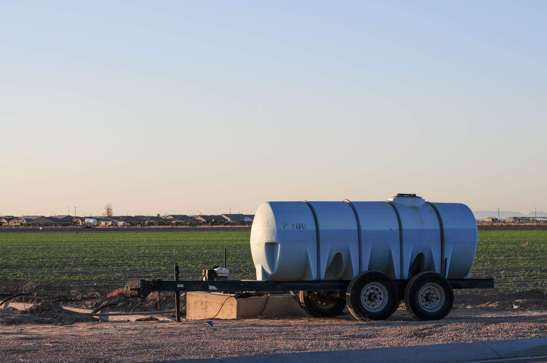 A large tank is on a trailer in the middle of a field.
