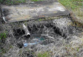 There is a hole in the ground with a pipe in it.