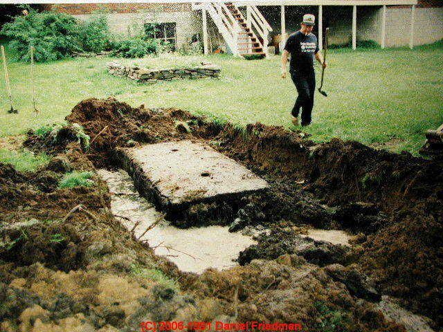 A man is digging in the dirt in a backyard