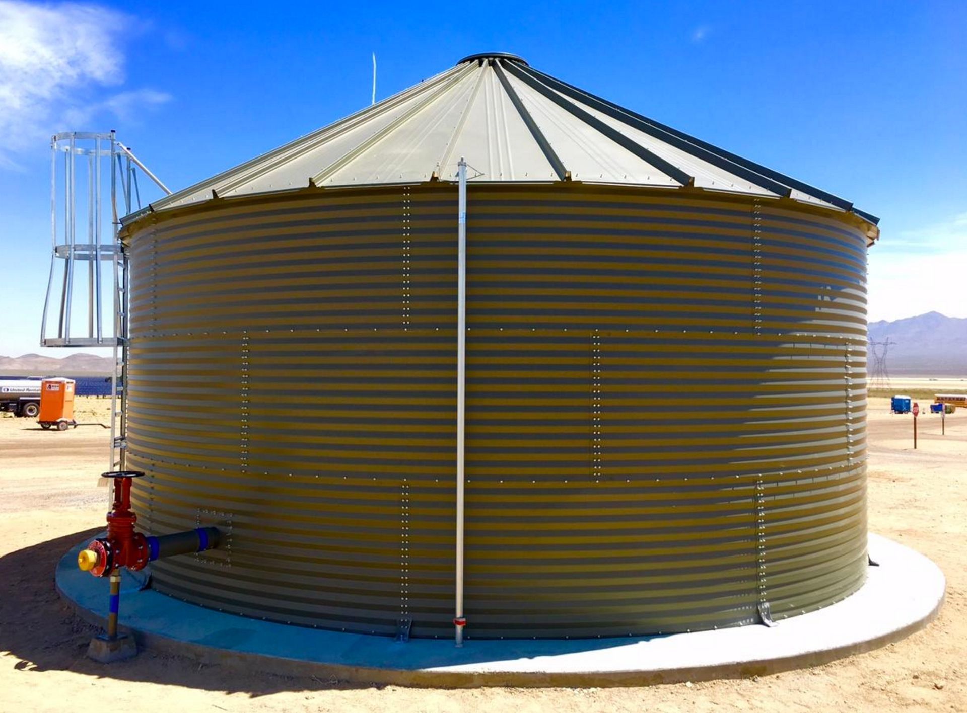 A large metal tank is sitting in the middle of a desert.