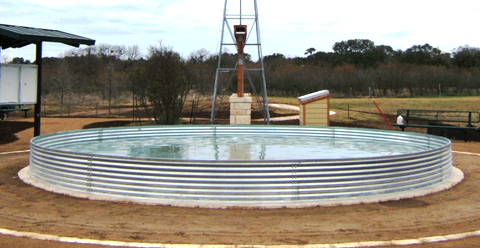 A large metal tank is sitting in the middle of a dirt field.