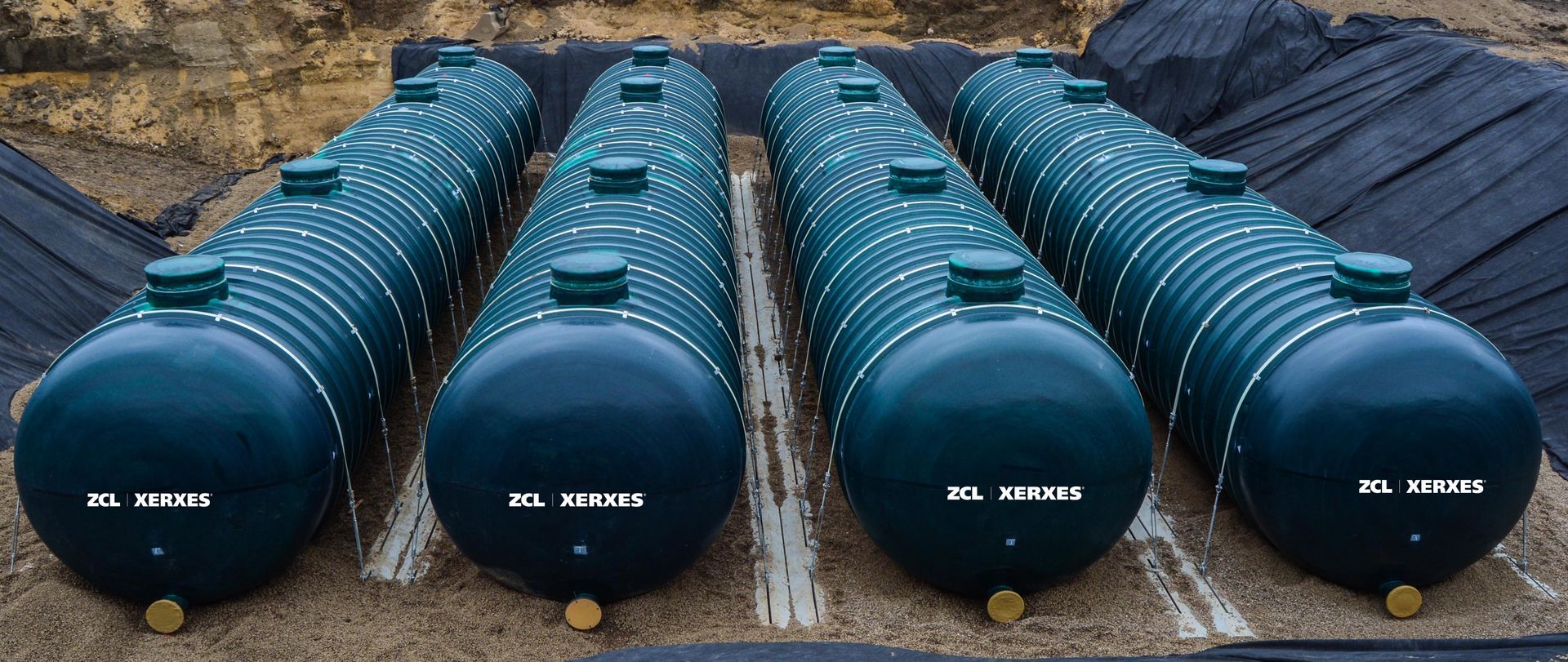 A row of blue tanks are lined up in a field.