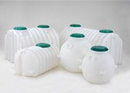 A group of white plastic barrels with green lids are sitting on top of each other on a table.