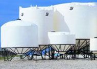 A group of white tanks sitting next to each other on top of a dirt field.