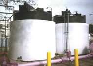 Two large white tanks are sitting next to each other in a parking lot.