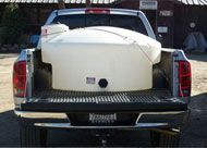 The back of a truck with a large white tank in the bed.