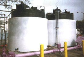 Two large white tanks are sitting next to each other next to pink pipes.