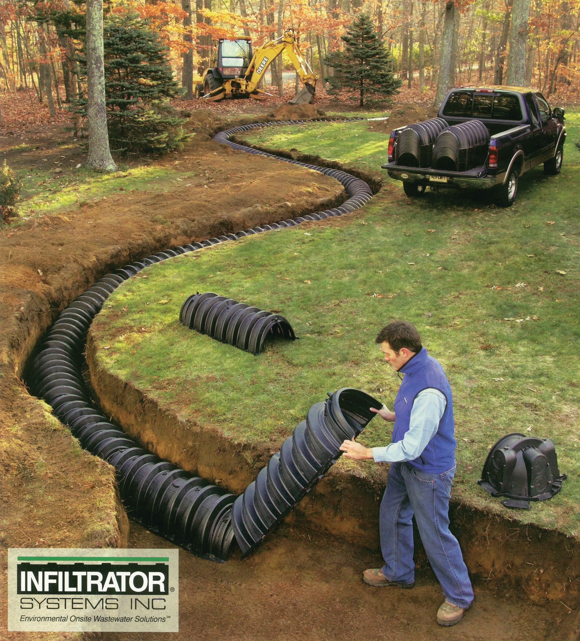 A man is working on a drainage system with a truck in the background