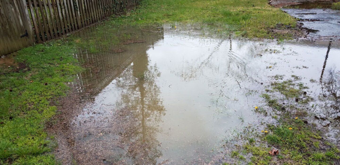 A large puddle of water in the middle of a yard.