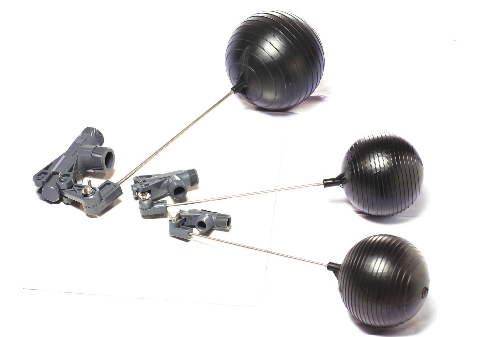 Three black balls are sitting on top of each other on a white surface.
