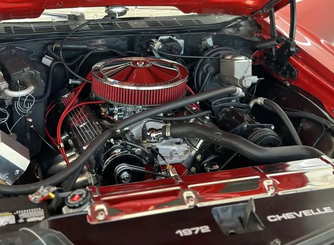 Red Chevrolet engine bay with a chrome air filter and black hoses under the open hood