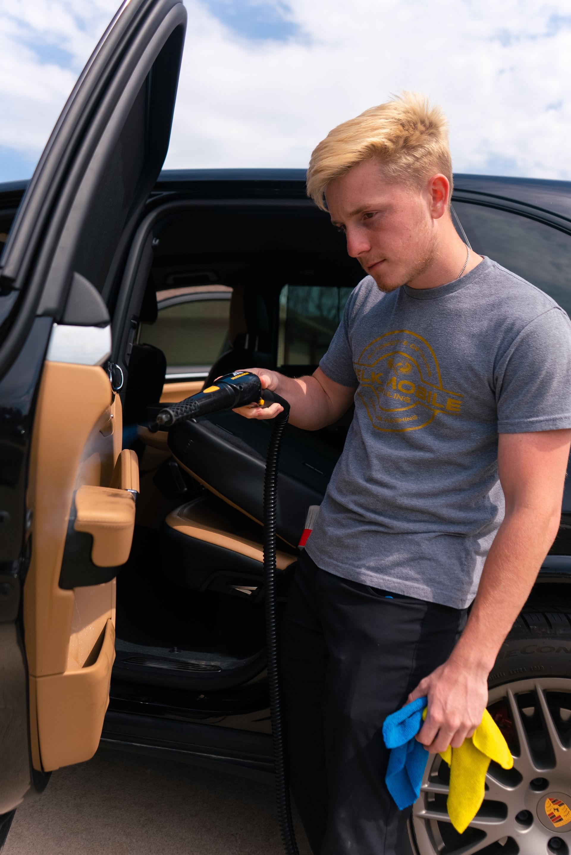 A person using a cleaning tool on a car door, holding a rag.