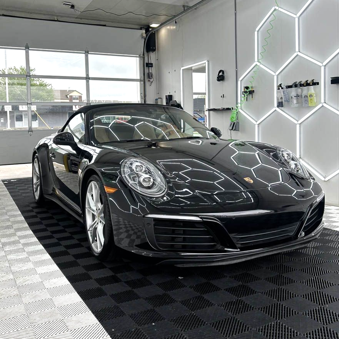Black Porsche sports car in a bright showroom with hexagonal wall lights