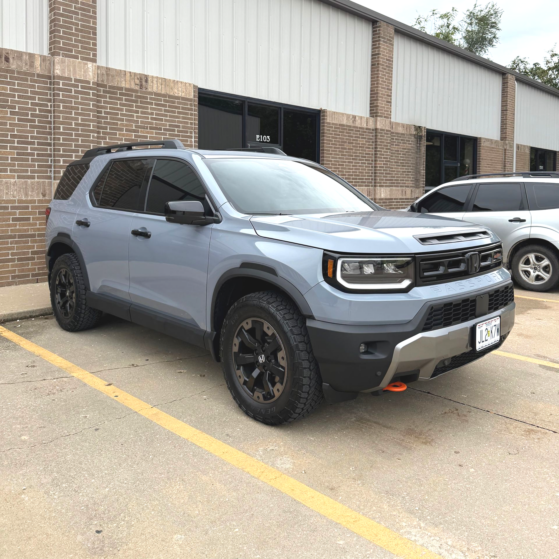 Gray Ford Bronco Sport parked in a parking lot, in front of a brick and metal building.