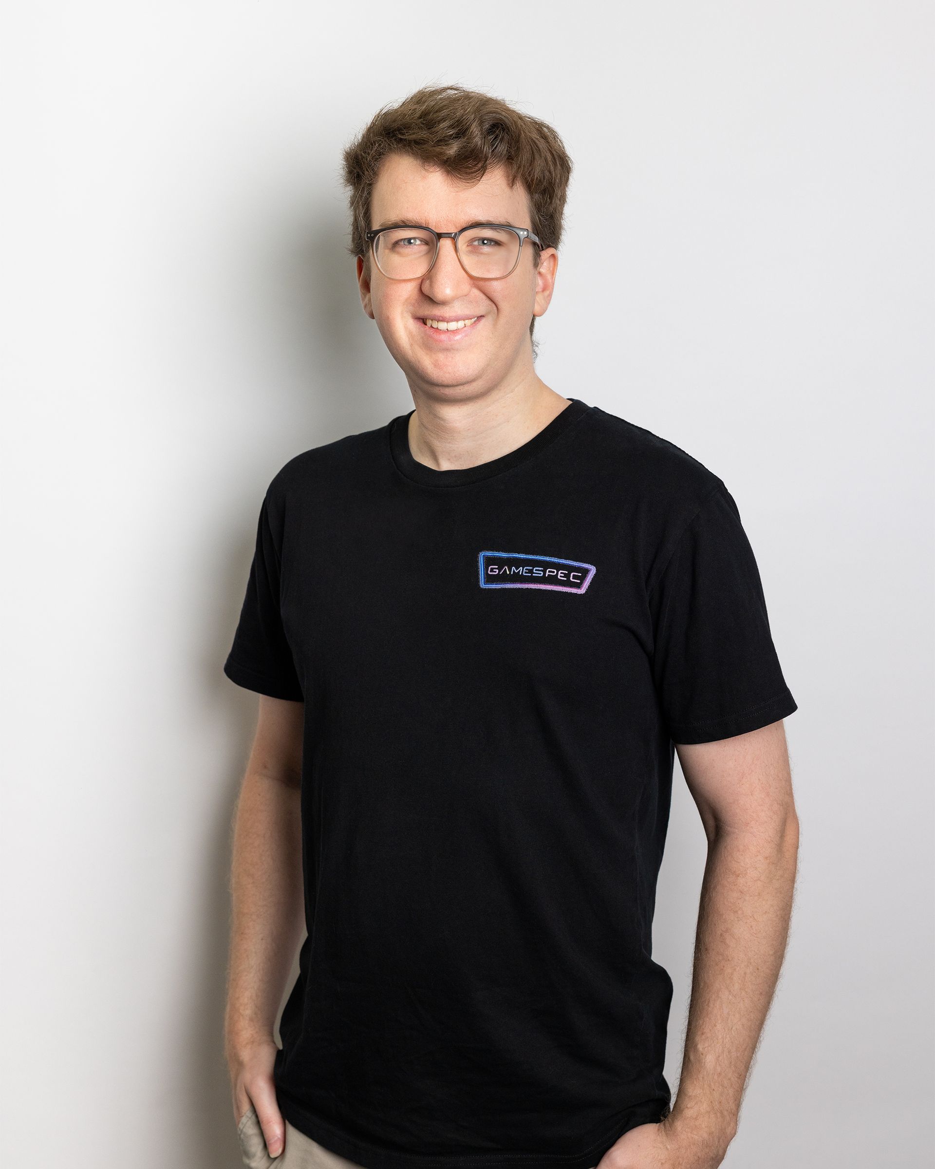 Smiling person in glasses wearing a black T-shirt against a light background