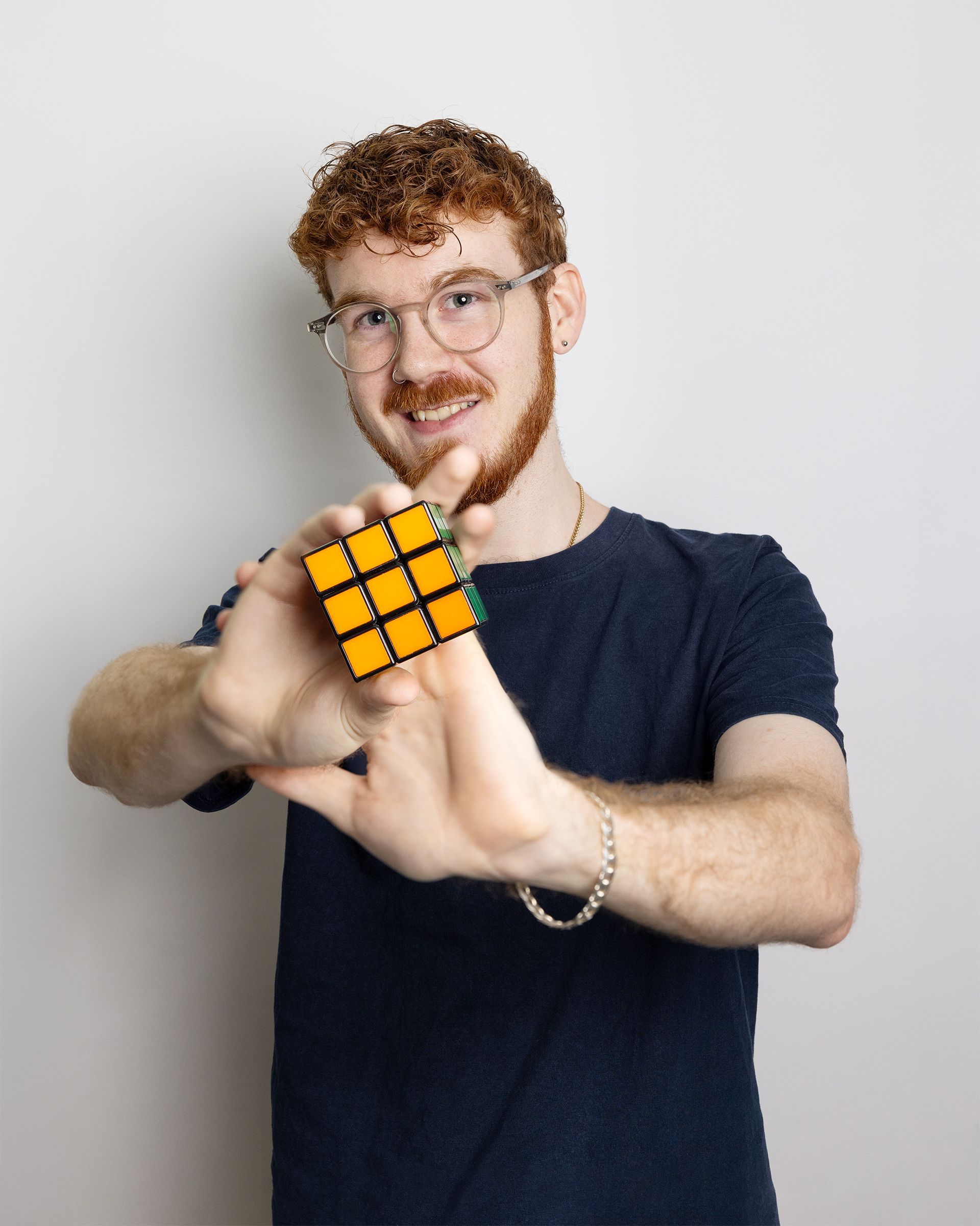 Person holding a Rubik’s Cube toward the camera against a plain light background