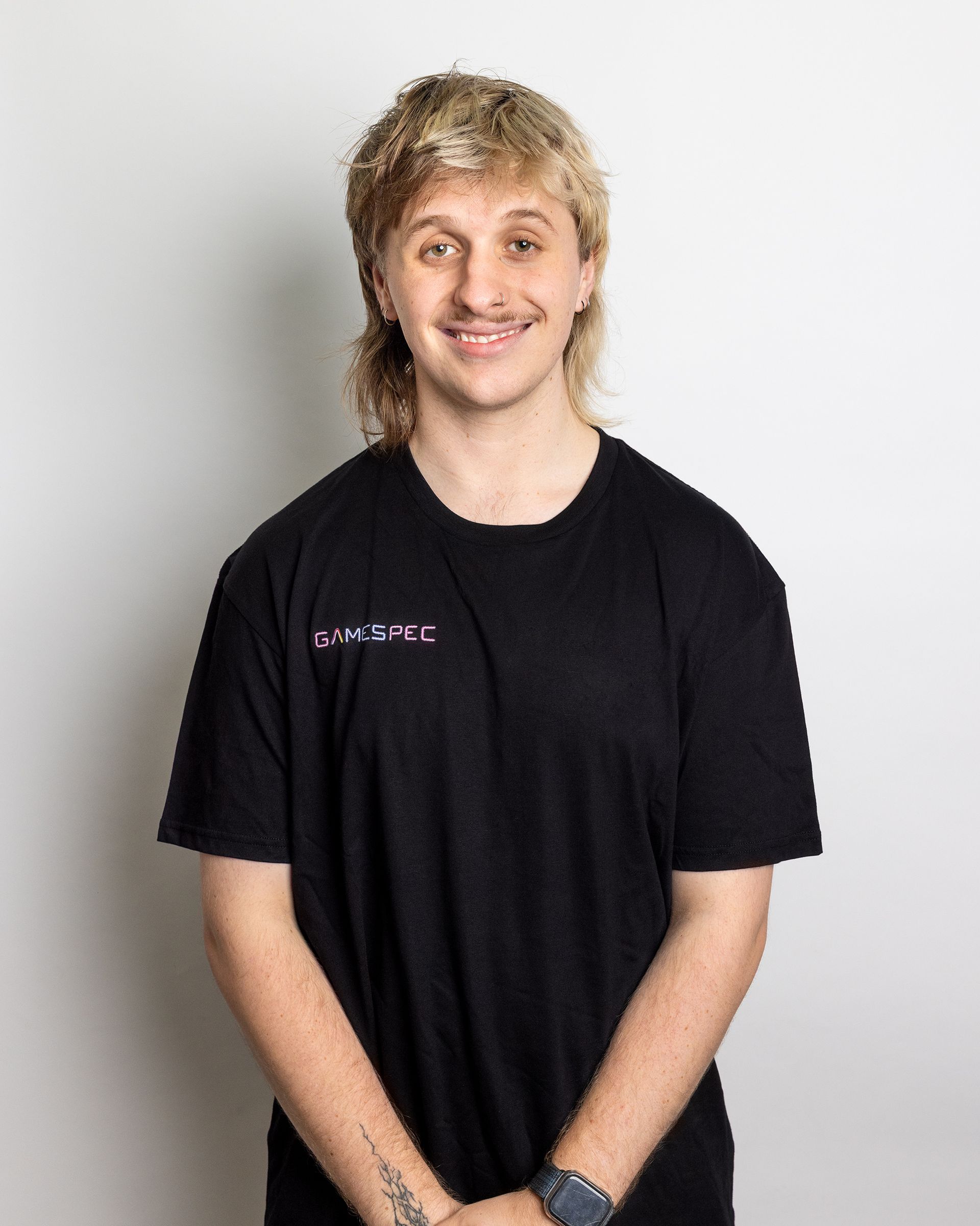 Person standing against a light background, wearing a black T-shirt and smiling.