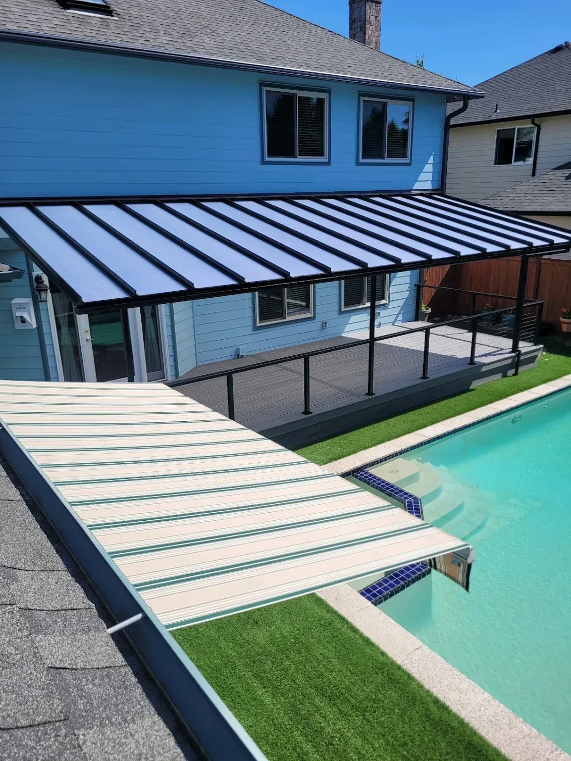 There is a swimming pool in the backyard of a house.