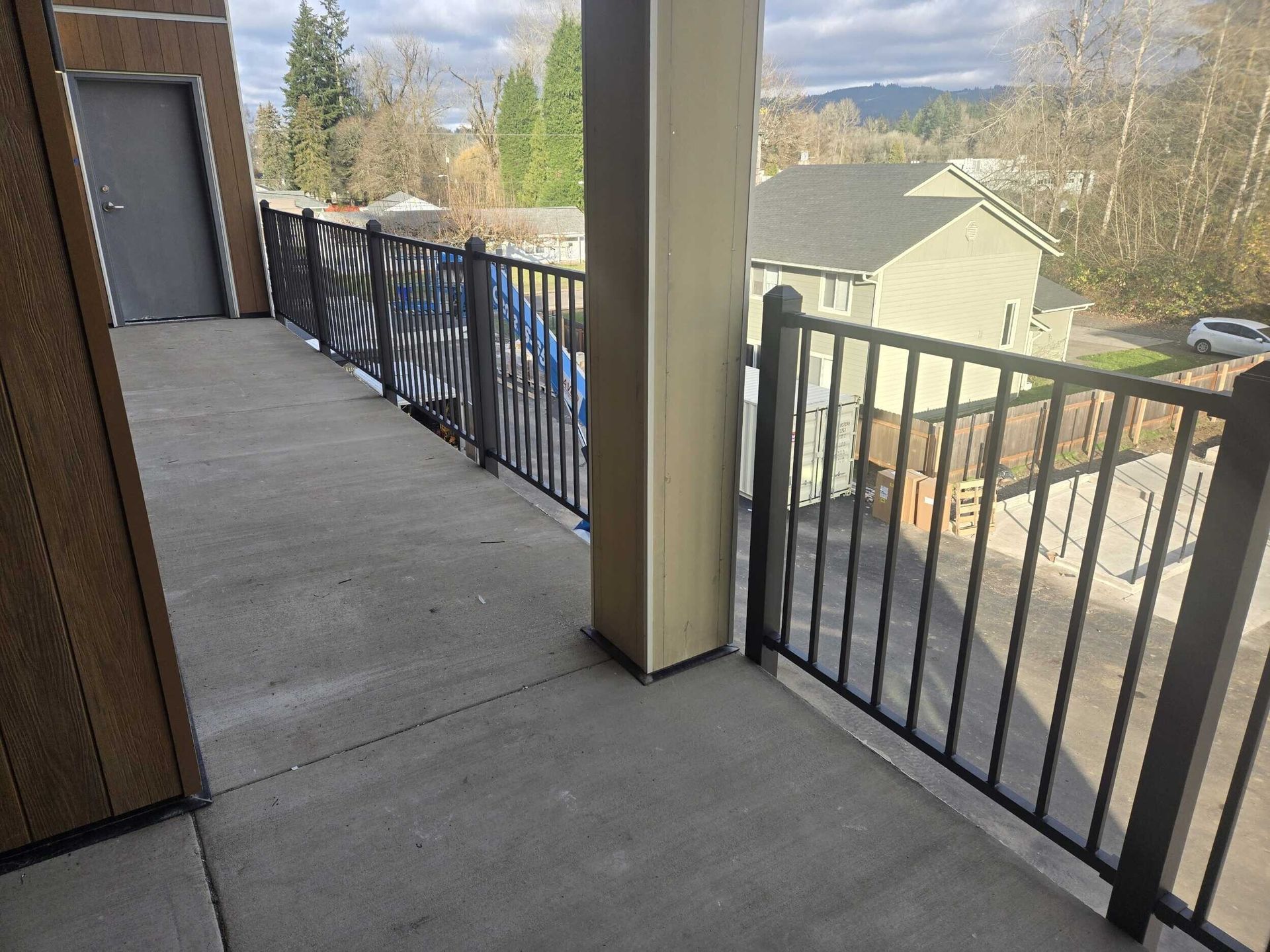 A balcony with a metal railing and a view of a house.
