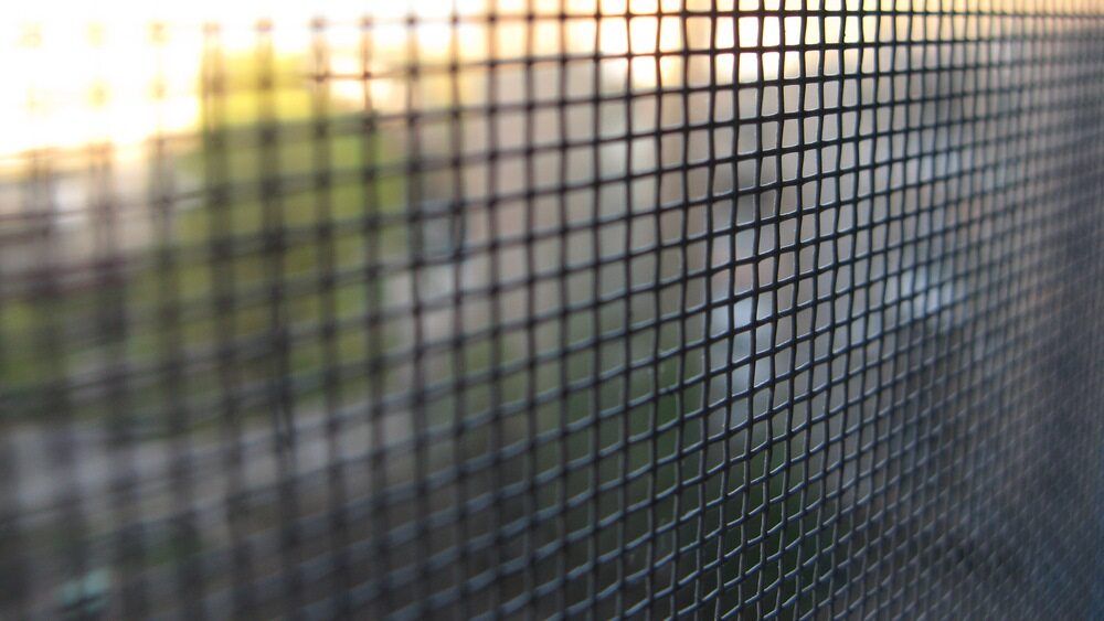 Close-Up of A Window Screen with Sunlight and A Softly Blurred Outdoor View Behind It — My Handyman Townsville In Garbutt, QLD