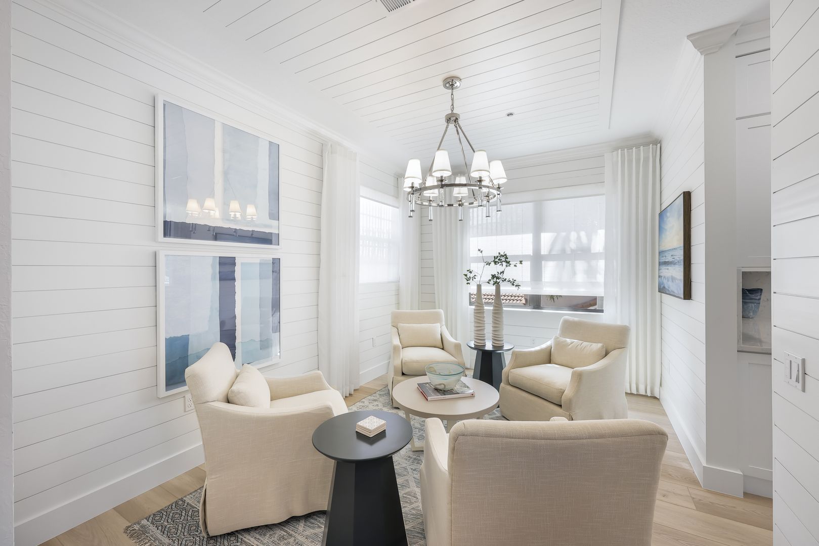 A living room with white furniture and a chandelier.