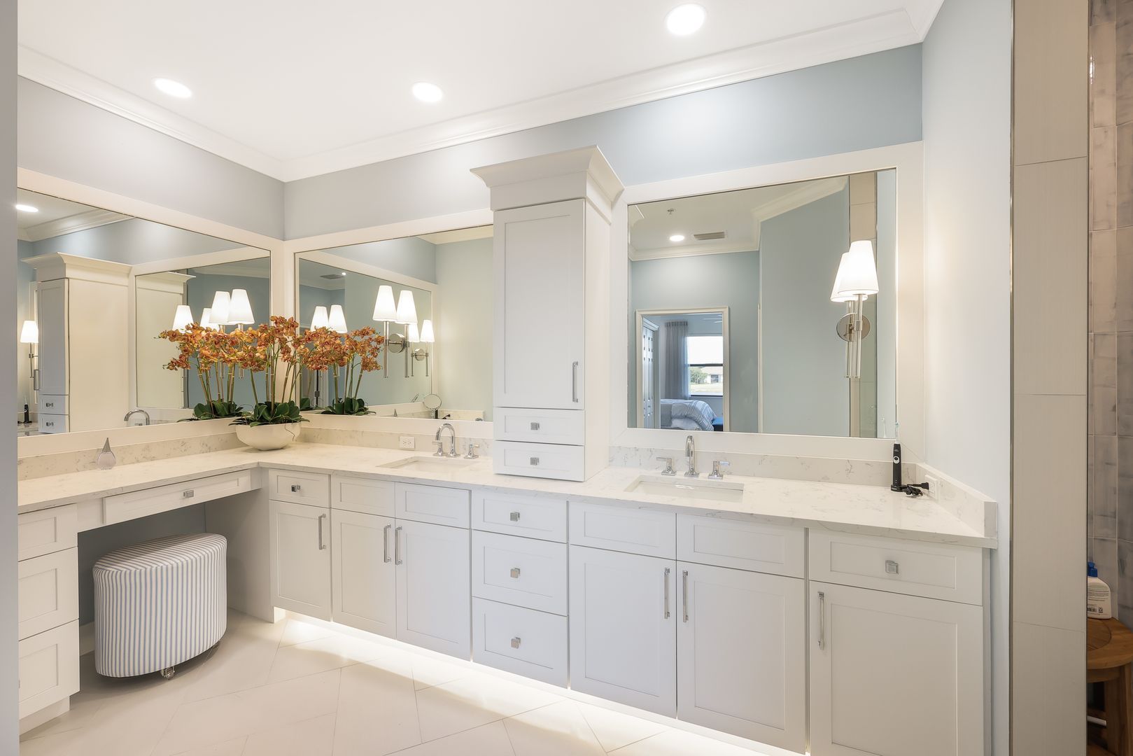 A bathroom with two sinks , two mirrors and a stool.