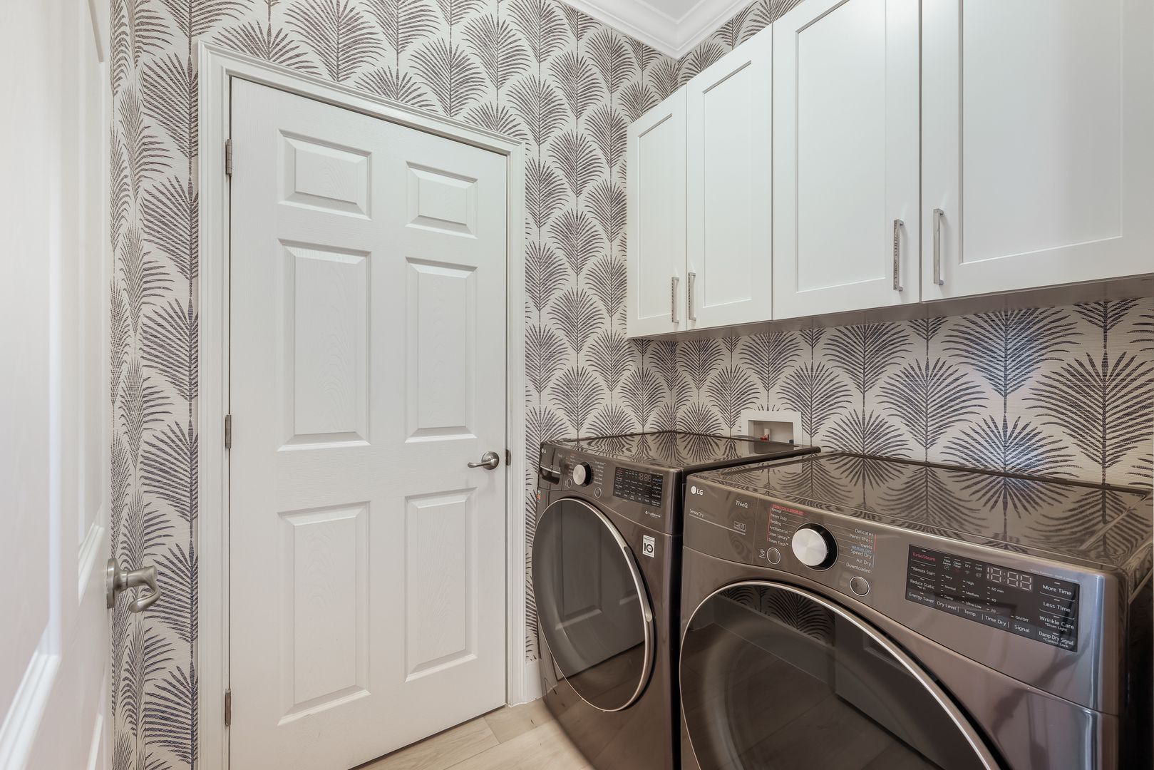 A laundry room with a washer and dryer and white cabinets.